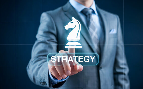 Businessman touching virtual "STRATEGY" button with chess knight icon for business planning, leadership, and digital solutions.