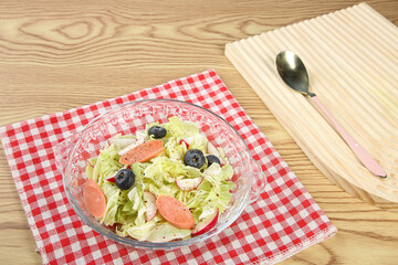 Fresh Cabbage Salad with Radishes and Olives in Glass Bowl on Wooden Table