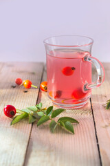 rose hips tea in glass cup on wooden background