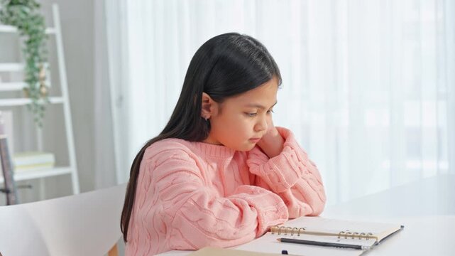 Asian young kid girl struggling with homework in living room at home.