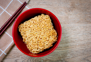 Instant noodles in a red bowl on a wooden background. Asian and Chinese fast food concept.
