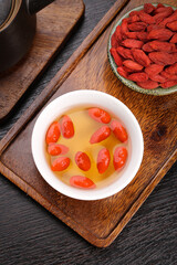 Goji Berry Tea with Dried Wolfberries in Bowl on Wooden Tray - Traditional Chinese Herbal Health Drink