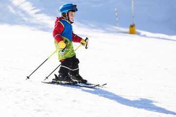 Child skiing downhill on sunny winter day