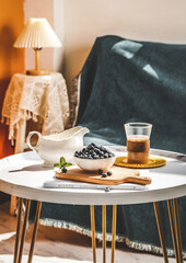 Fresh Blueberries and Coffee on Stylish Round Table in Cozy Living Room Interior