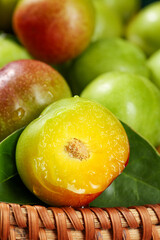Fresh Ripe Plums Cut in Half Showing Juicy Yellow Flesh in Wicker Basket Display