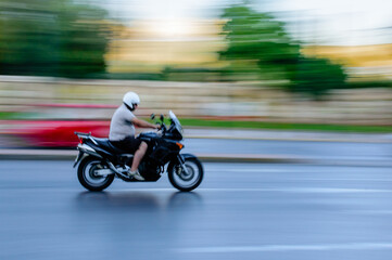Motorcycle rider with helmet on city street in Athens, Greece.