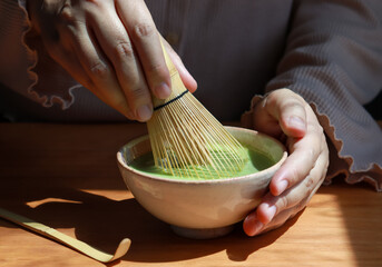 Brewing matcha green tea with a bamboo whisk, a traditional Japanese green tea brewing ceremony