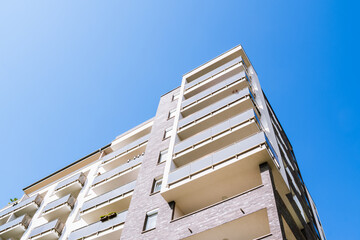 Modern residential building with stacked balconies and clean geometric design rising against a...