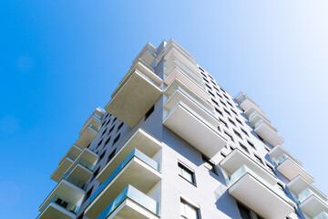 Modern residential building with stacked balconies and clean geometric design rising against a...
