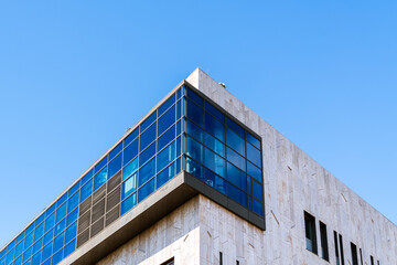 Contemporary office building with reflective blue windows, white façade, and minimal yellow accents under bright sky.