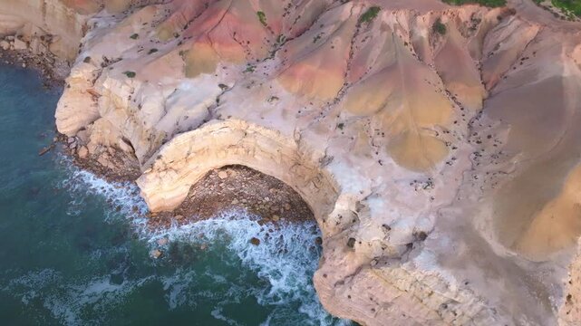 Aerial view of rugged cliffs with colorful rock formations meeting the turquoise sea, creating a stunning contrast, Port Willunga, South Australia, Australia.
