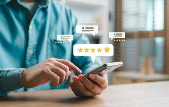 Close-up of a person using a smartphone to leave a five-star review with digital rating icons, concept of customer satisfaction, feedback, online reputation and user experience.