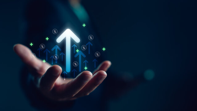 Businessman hand holding virtual glowing arrow up icon, representing business growth, financial performance, investment success and positive economic trend with percentage symbols.