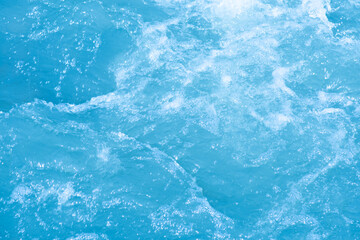 Obraz premium Blue water with ripples on the surface. Defocus blurred transparent blue colored clear calm water surface texture with splashes and bubbles. Water waves with shining pattern texture background.