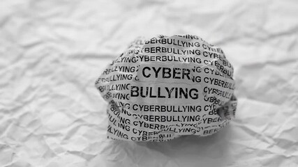 Crumpled paper ball with words Cyberbullying on crumpled white paper background.