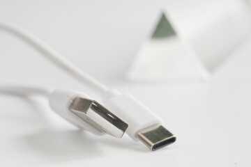 White cable with USB‑A and USB‑C connectors on a white backdrop, a small glass prism in the blur; connector comparison for charge and data. Photo