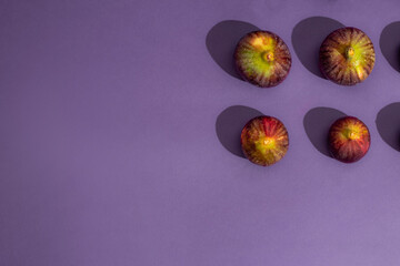 Pattern made of fresh figs on purple background. Flat lay, top view. Food Photo. Creative scheme of the whole and sliced figs  inscribed in a rectangle. Copy space