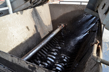 A waste tire crushing machine in operation, with water being sprayed to prevent dust, an industrial...