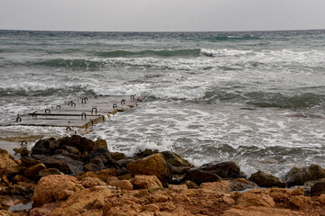 A wastewater discharge pipe extending into the rough sea, surrounded by concrete structures and...