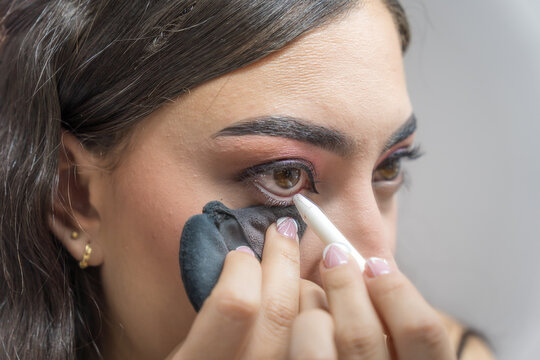 Woman applying eyeliner during makeup session at home