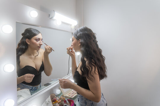 Woman applying makeup in mirror at home session