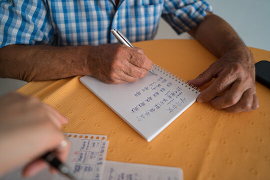 Senior man learning Mandarin with teacher's guidance