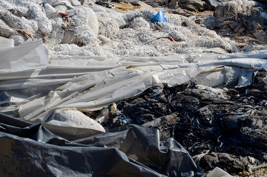 A large pile of oil-soaked absorbents used for an oil spill accident, disposed of on land, illustrating the complex and environmentally challenging process of cleaning up toxic spills.