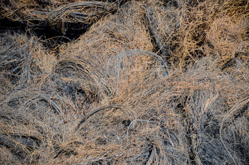 An intricate texture shot showing tangled steel wires and rubber fibers, the remnants of recycled vehicle tires, highlighting the details of industrial waste processing.