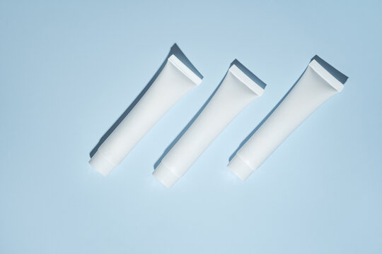 Top view of white cosmetic cream tubes on blue background