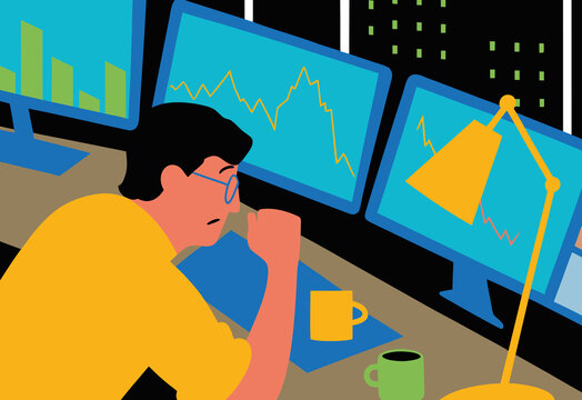 A professional is seated at a desk, intently observing multiple computer screens displaying market data and graphs