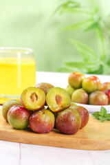 Fresh Ripe Plums Cut in Half on Wooden Board with Orange Juice Glass - Healthy Organic Stone Fruit Display