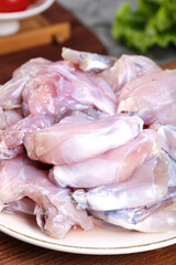 Fresh Raw Frog Legs on White Plate Ready for Gourmet Cooking and Culinary Preparation