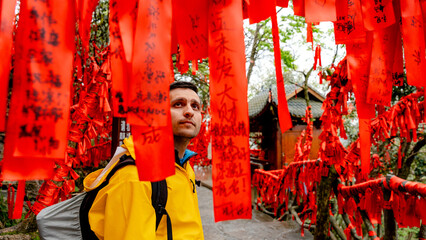 Man Observing Red Wish Ribbons Hanging from Trees in China