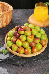 Fresh Ripe Plums in Wicker Basket Display with Orange Juice on Slate Background