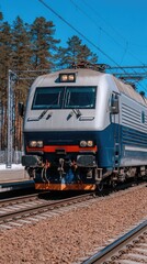 Fototapeta premium Electric train approaches a station surrounded by pine trees on a clear day in early spring
