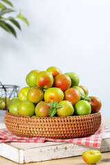Fresh Colorful Plums in Wicker Basket with Mint on Rustic Wood Background