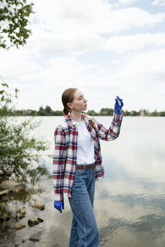 Young female biologist examining water sample outdoors