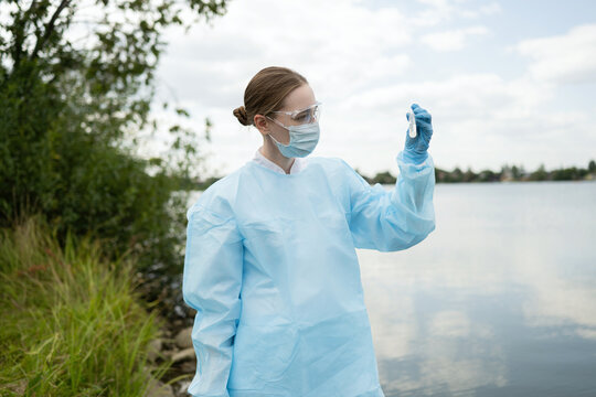 Young female biologist examining water sample outdoors
