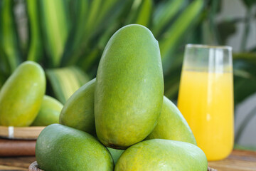 Fresh Green Mangoes with Tropical Juice on Wooden Table Against Palm Leaves Background