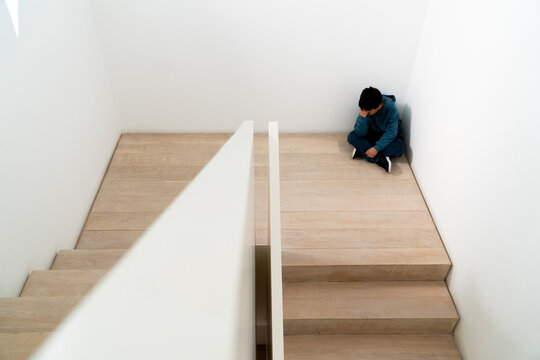 Preteen boy sitting alone on school stairs feeling sad