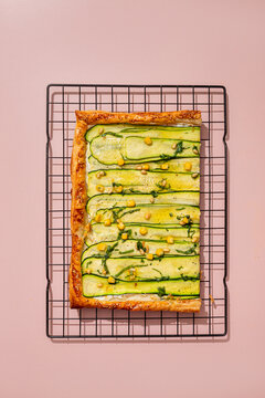 Top view of courgette tart on cooling rack with pink background