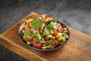 Spicy Asian Vegetable Stir Fry with Mixed Greens and Chili Peppers in Black Bowl on Wooden Board