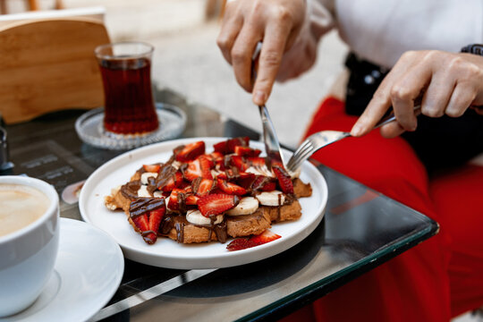 Person enjoys waffles with fruit in cozy cafe - Powered by Adobe