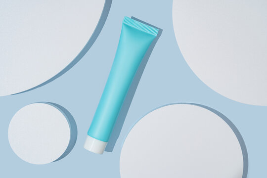 Cosmetic package on blue background with shapes