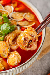 Fresh seafood soup with octopus and clams in spicy red broth with chopsticks