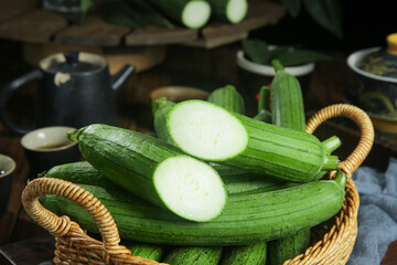 Freshly picked loofah vine gourds in basket with traditional cookware - Shouguang organic farming produce
