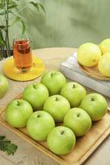 Fresh Green Asian Pears and Yellow Fruit on Wooden Board with Tea Glass in Natural Kitchen Setting