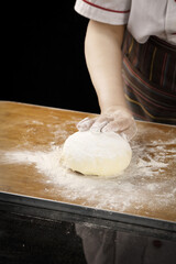 Baker Kneading Fresh Wheat Dough with Flour on Wooden Board in Professional Kitchen