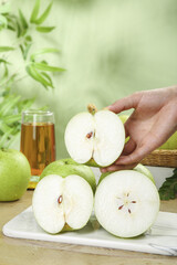 Fresh Green Apple Halves on Wooden Cutting Board with Hand Holding Fruit Slice