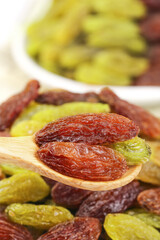Red and Green Dried Raisins on Wooden Spoon with Mixed Dried Fruits Background